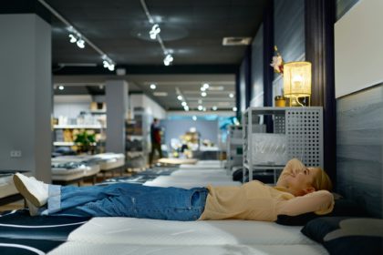 Woman choosing bed mattress in furniture store